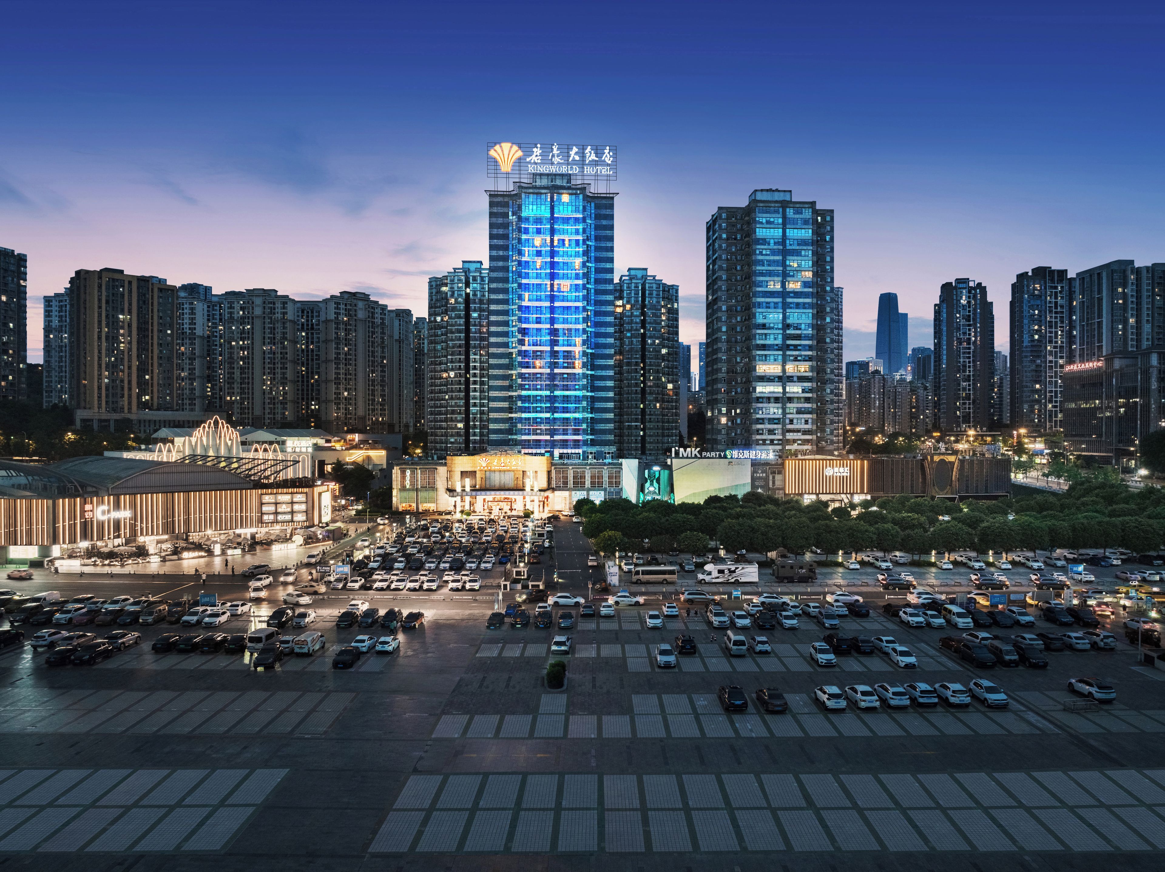 A cityscape with a prominent hotel building, a parking lot, and surrounding high-rise buildings.