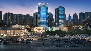 A cityscape with a prominent hotel building, a parking lot, and surrounding high-rise buildings.