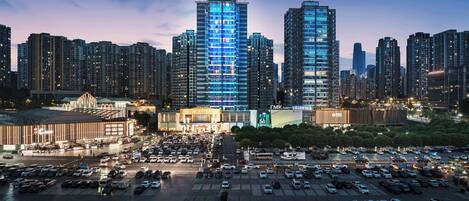 A cityscape with a prominent hotel building, a parking lot, and surrounding high-rise buildings.