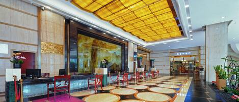 A hotel lobby with a reception desk, seating area, and a large window.