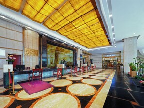En hotellobby med en receptionsdisk, en sittgrupp och ett stort fönster.