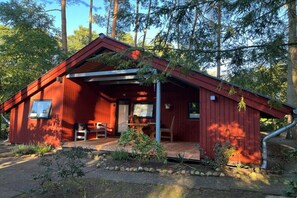 En röd stuga med en veranda, en tv och ett litet bord.