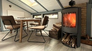 Um quarto acolhedor com lareira, uma mesa de jantar com cadeiras e um claraboia.