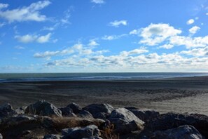 Een strand met een heldere lucht en een rotsachtige voorgrond.