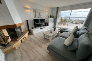 Een moderne woonkamer met een open haard, een bank, een salontafel en een televisie.
