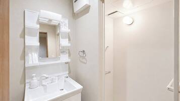 A bathroom with a white sink, mirror, and a shower area.