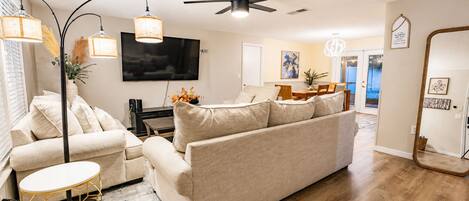 A living room with a sofa, a coffee table, a TV, and a ceiling fan.