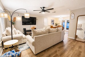 A living room with a sofa, a coffee table, a TV, and a ceiling fan. - Christmas Magic Starts Here/Book now and unwrap a special stay surprise! (BRADENTON)