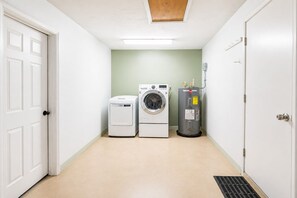Uma lavanderia com máquina de lavar, secadora e aquecedor de água.