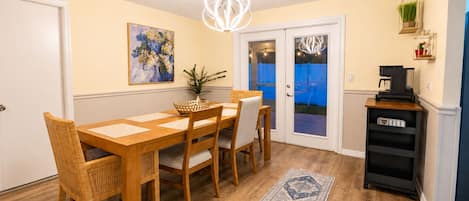 A dining area with a wooden table and chairs, a coffee machine, and a decorative rug.