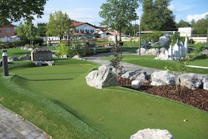 A miniature golf course with a house model, rocks, and trees. - Holiday home "Hochplatte" (Lechbruck)