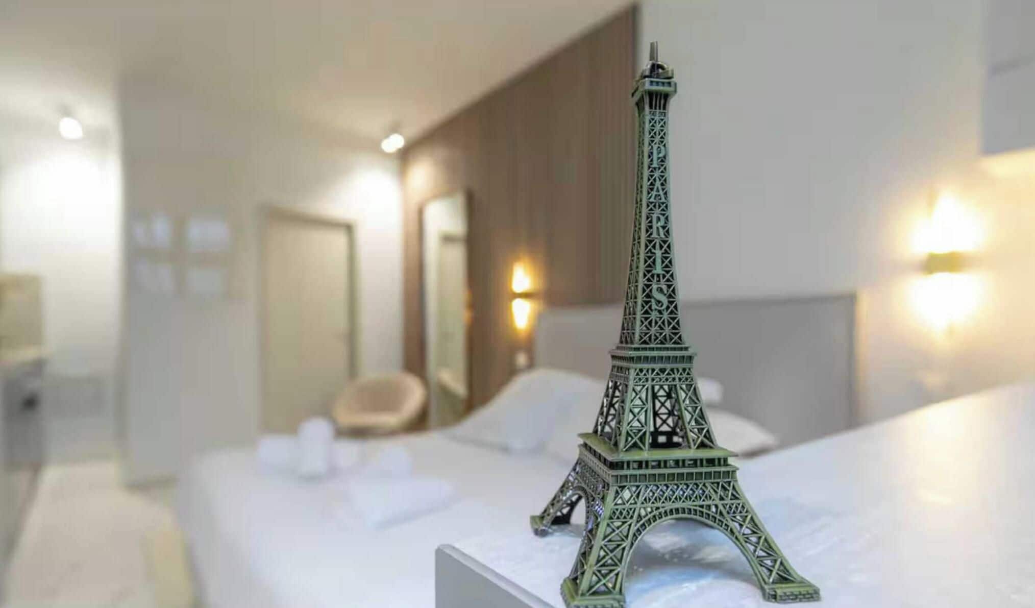 A model of the Eiffel Tower on a bed in a hotel room.
