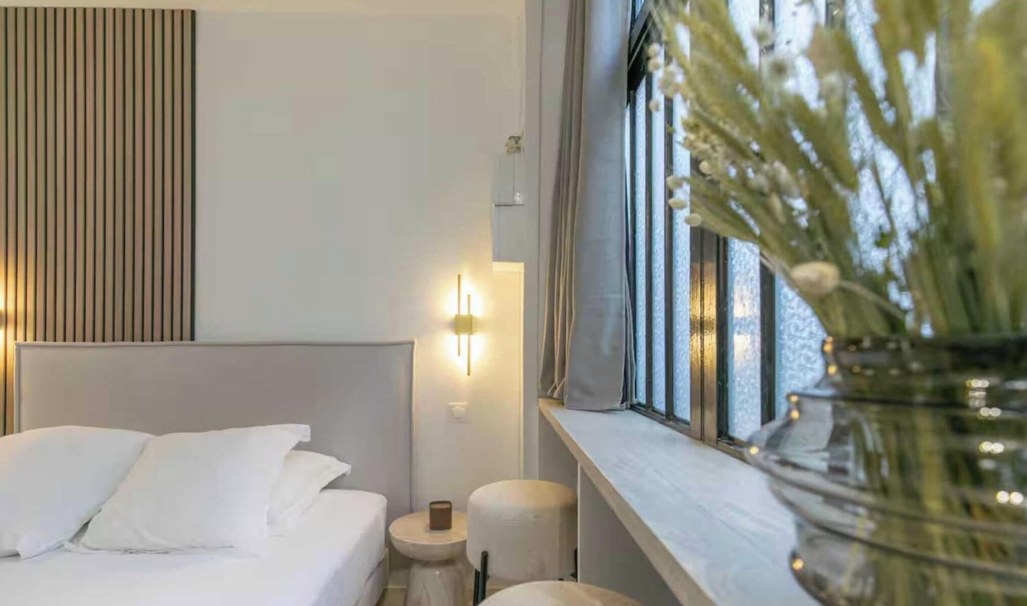 Ein Hotelzimmer mit Bett, Nachttisch, Lampe und einem Fenster mit Blick.