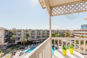 A multi-story hotel with balconies, a swimming pool, and outdoor seating areas. - Tidal Treasure at the Victorian (Galveston)