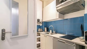 Een compacte keuken met een ingebouwde oven, een spoelbak en een koffiezetapparaat.