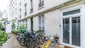 Een rij fietsen geparkeerd voor een gebouw met een grote glazen deur en een welkomstmat.