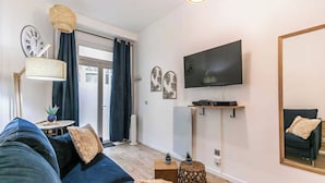 Een moderne woonkamer met een bank, een flatscreen televisie aan de muur en een grote spiegel.