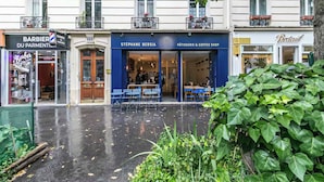 Een straat met winkelgefaciliteiten, waaronder een kapperszaak en een patisserie.