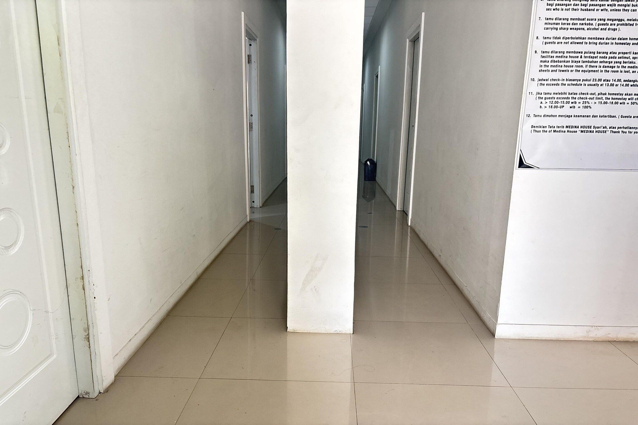 A corridor with a tiled floor leading to a door at the end.