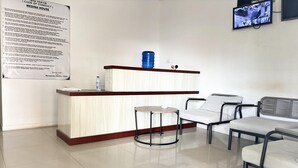 A reception area with a counter, chairs, and a television mounted on the wall. - Relaxing Stay at Medina House (Banda Aceh)