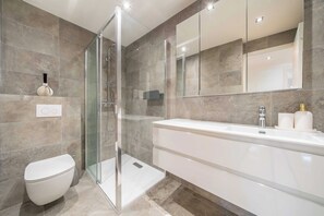 A modern bathroom with a glass-enclosed shower, a white toilet, and a large vanity with a mirror. - Elegant apartment - AC- 2BR/5P - Cannes (Cannes)