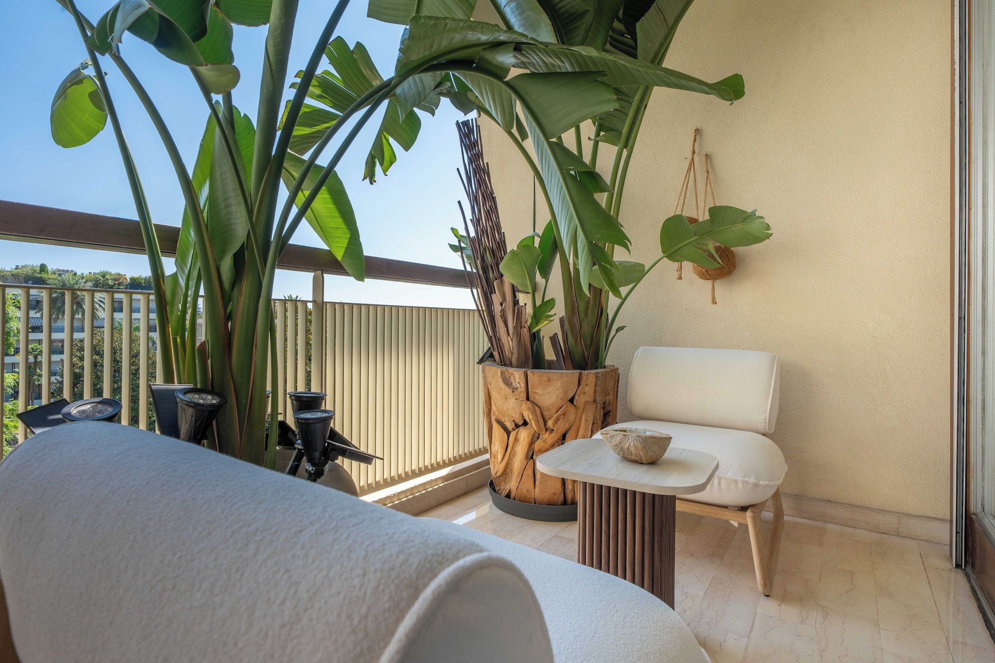 A balcony with a sofa, a small table, and a potted plant.