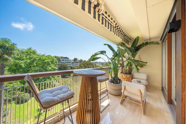 A balcony with a wooden table, two chairs, and potted plants. - Elegant apartment - AC- 2BR/5P - Cannes (Cannes)
