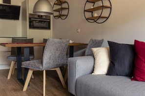 A modern living room with a grey sofa, two grey chairs, a wooden dining table, and a red pillow. - Apartment with 1 bedroom (St. Georgen am Kreischberg)