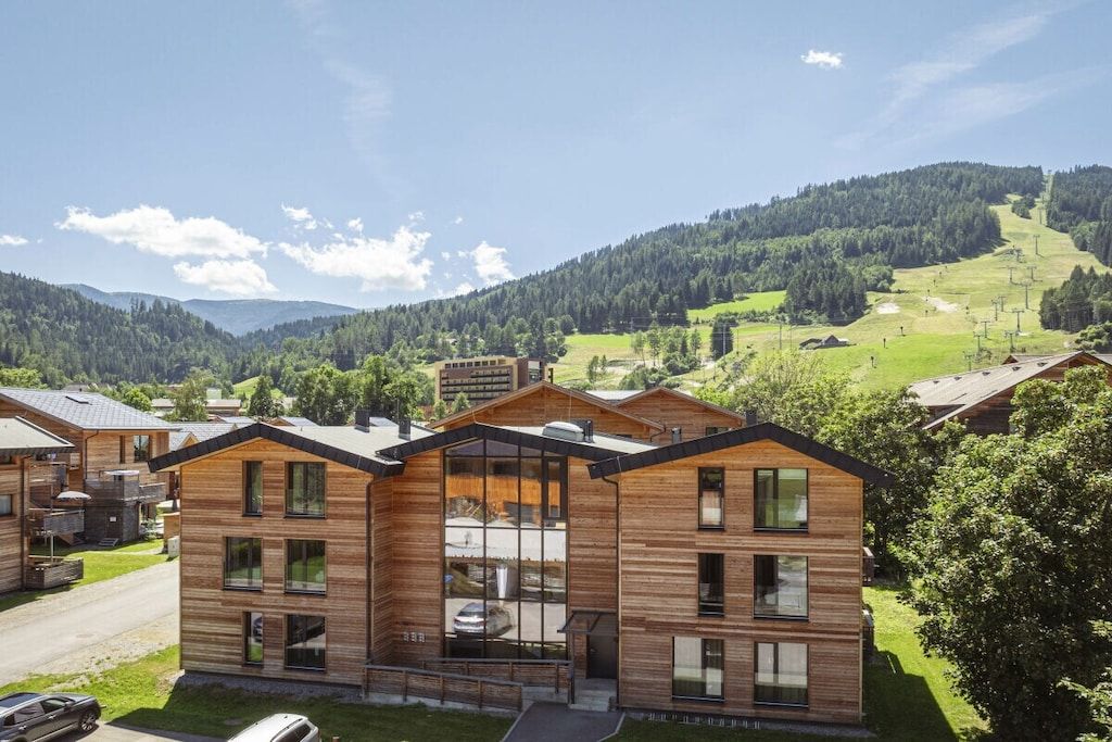 A modern wooden building with multiple windows and a clear view of the surrounding landscape.