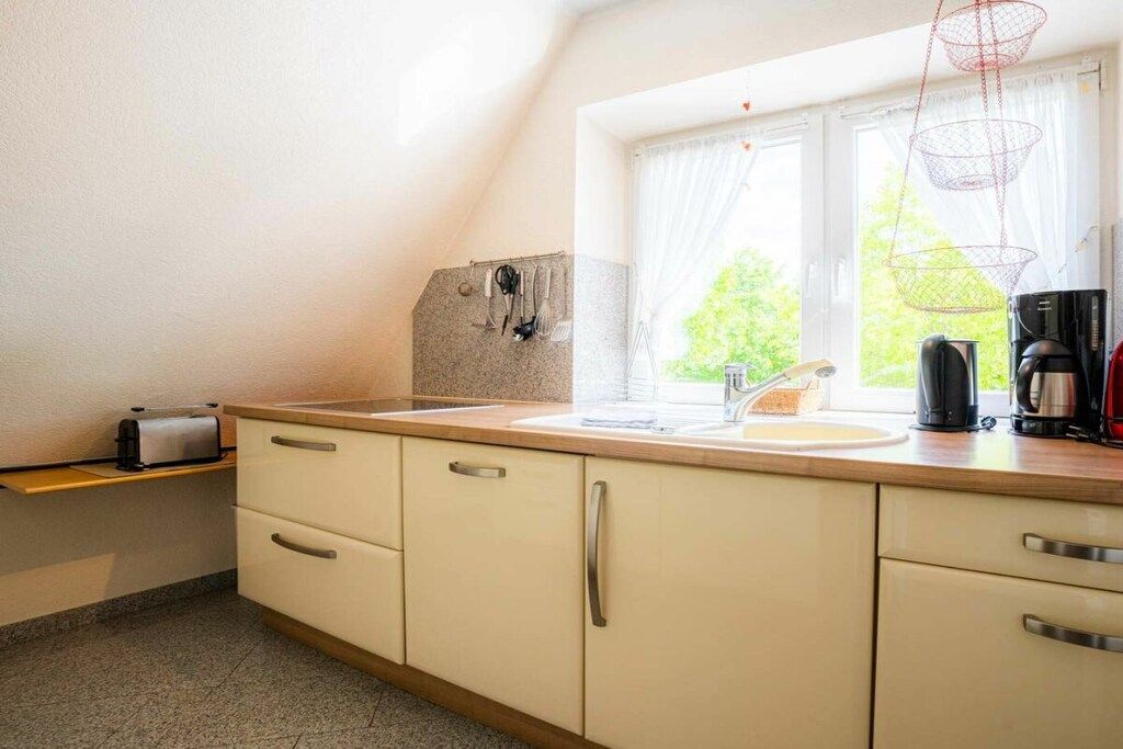 Et køkken med et vindue, en brødrister, en kaffemaskine og en hængende lampe.