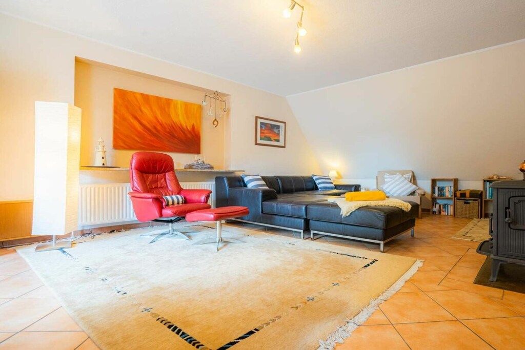 Ein Wohnzimmer mit einem roten Sessel, einem grauen Sofa, einem Kamin und einer Heizung.