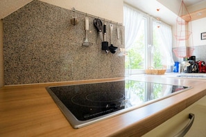 Eine Küche mit einer Granit-Arbeitsplatte, einem integrierten Induktionskochfeld und verschiedenen Küchenutensilien, die an der Wand hängen.