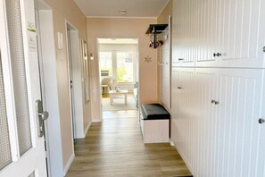 A hallway with a bench, a coat rack, and a door with a textured glass panel. - Holiday apartment with 1 bedroom (Wyk auf Föhr)