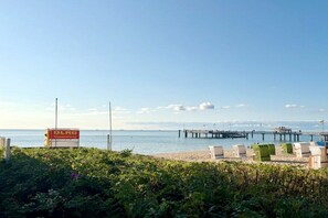 A beach with a pier, lounge chairs, and a sign for a BLAG restaurant. - Holiday apartment with 1 bedroom (Wyk auf Föhr)