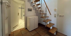 Ein Flur mit einer Holztreppe, einem weißen Schrank und einer Tür zu einem weiteren Raum.