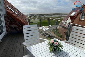 A balcony with white chairs and a table, overlooking a coastal landscape. - Apartment 260 - Dünenliebe (Juist)