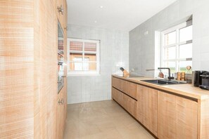 A modern kitchen with a wooden countertop, a sink, and a window with a view of a brick building. - 238 - Holiday home Watt (Juist)