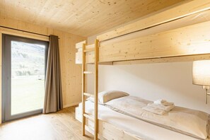 A bunk bed room with a wooden ceiling, a window with curtains, and a bed with pillows and folded towels. - Apartment with 1 bedroom (St. Georgen am Kreischberg)