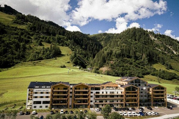 Un hotel de diverses plantes amb disseny modern, envoltat d'un paisatge de muntanya.