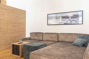 Un saló modern amb un sofà modular, un otomà petit i un quadre al mur.