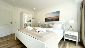 Et hotelværelse med en seng, et natbord med lampe, et klædeskab og et billede på væggen.