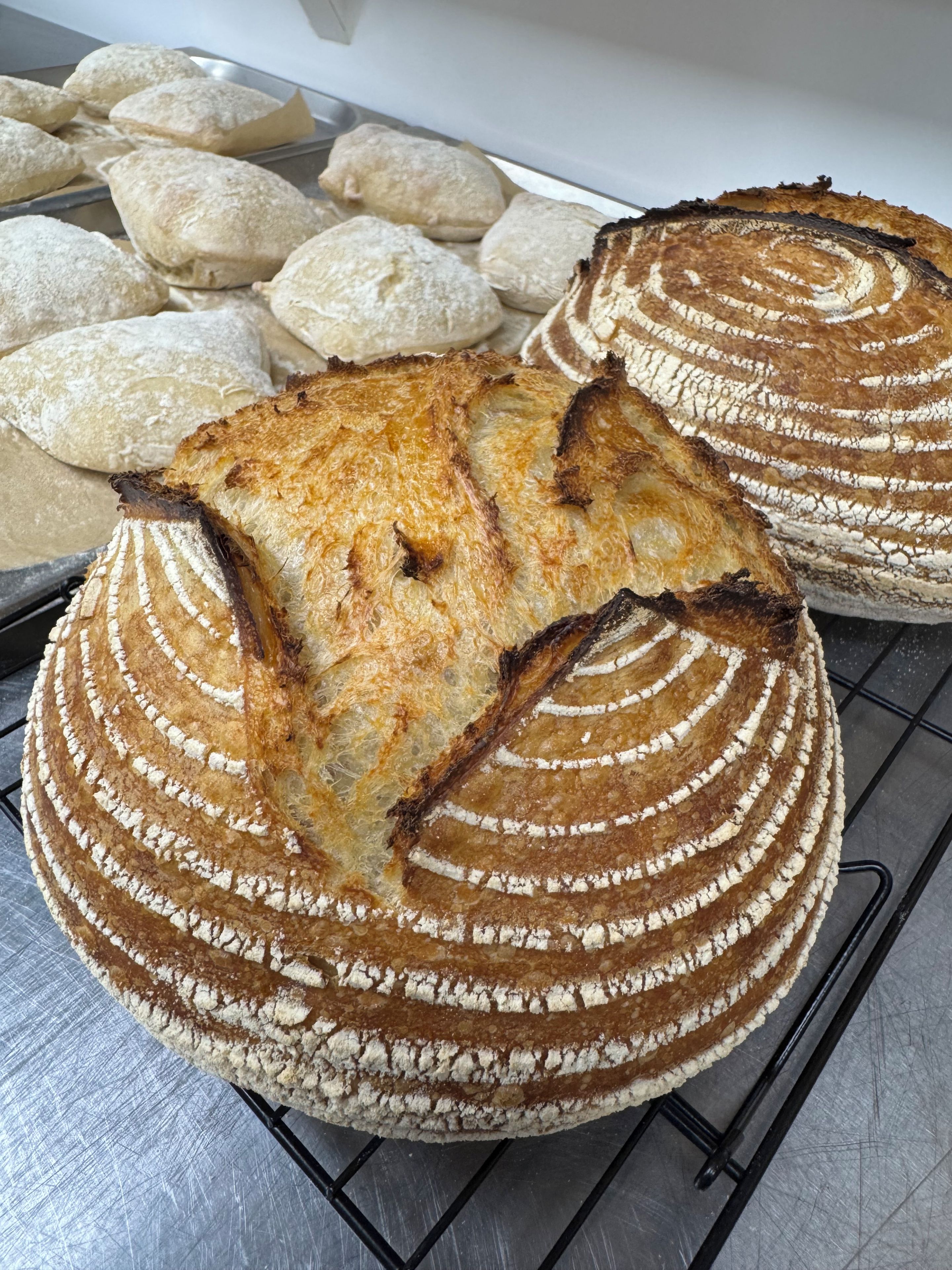 Une miche de pain à la croûte décorée, posée sur une grille métallique.