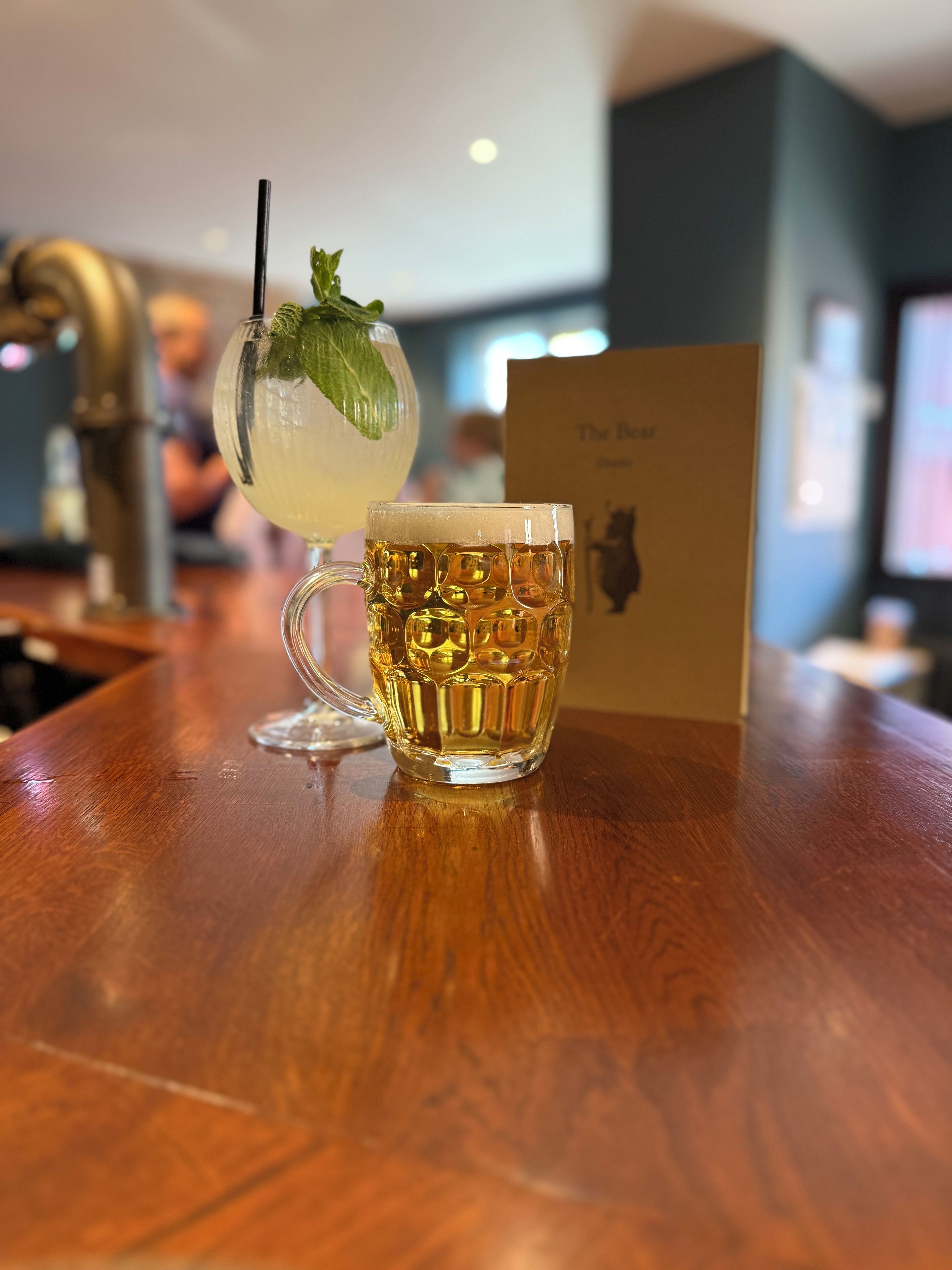 Een bar setting met een glazen mok en een cocktail op een houten ondergrond.