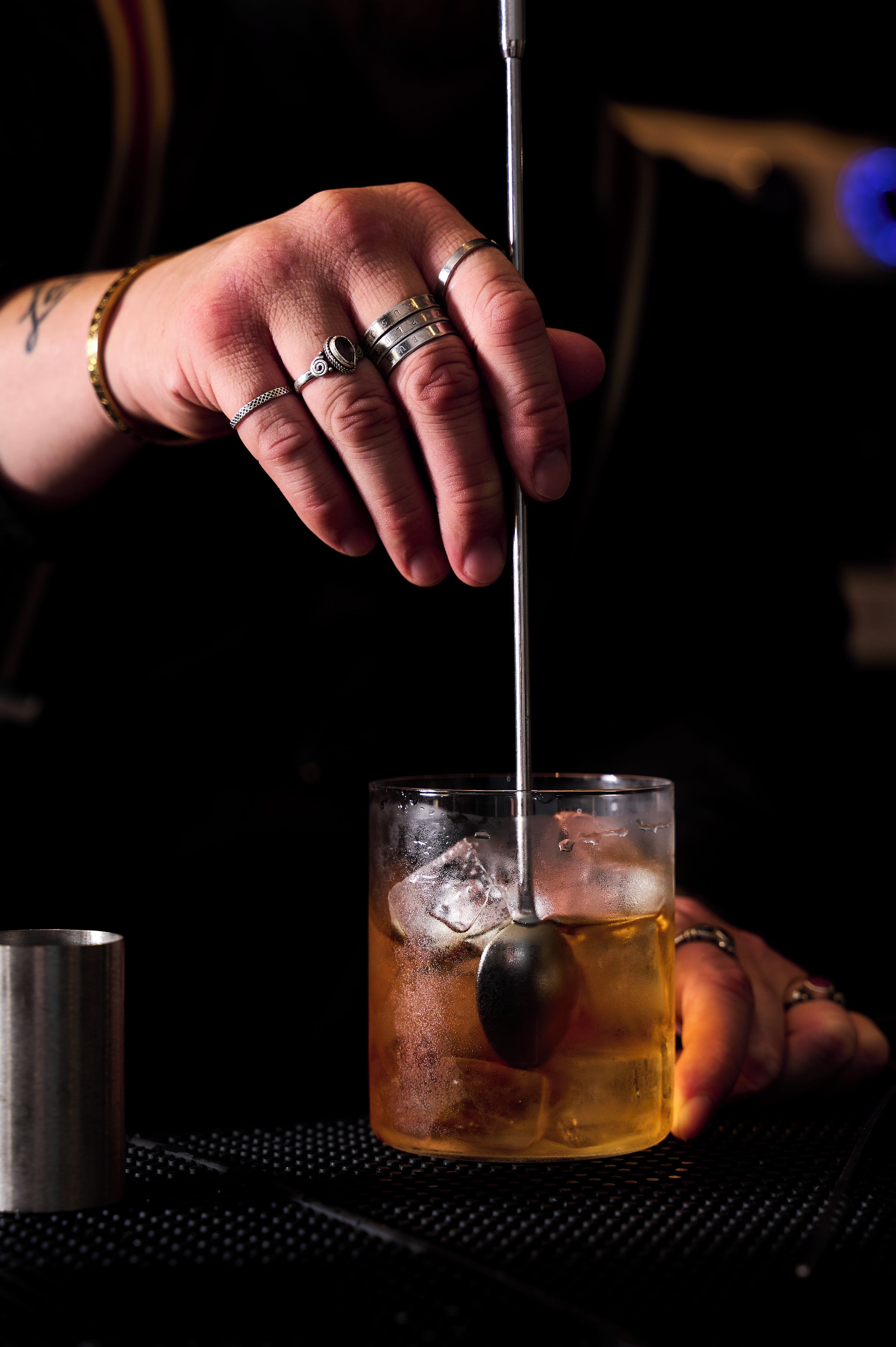A person pouring a drink into a glass with ice cubes.