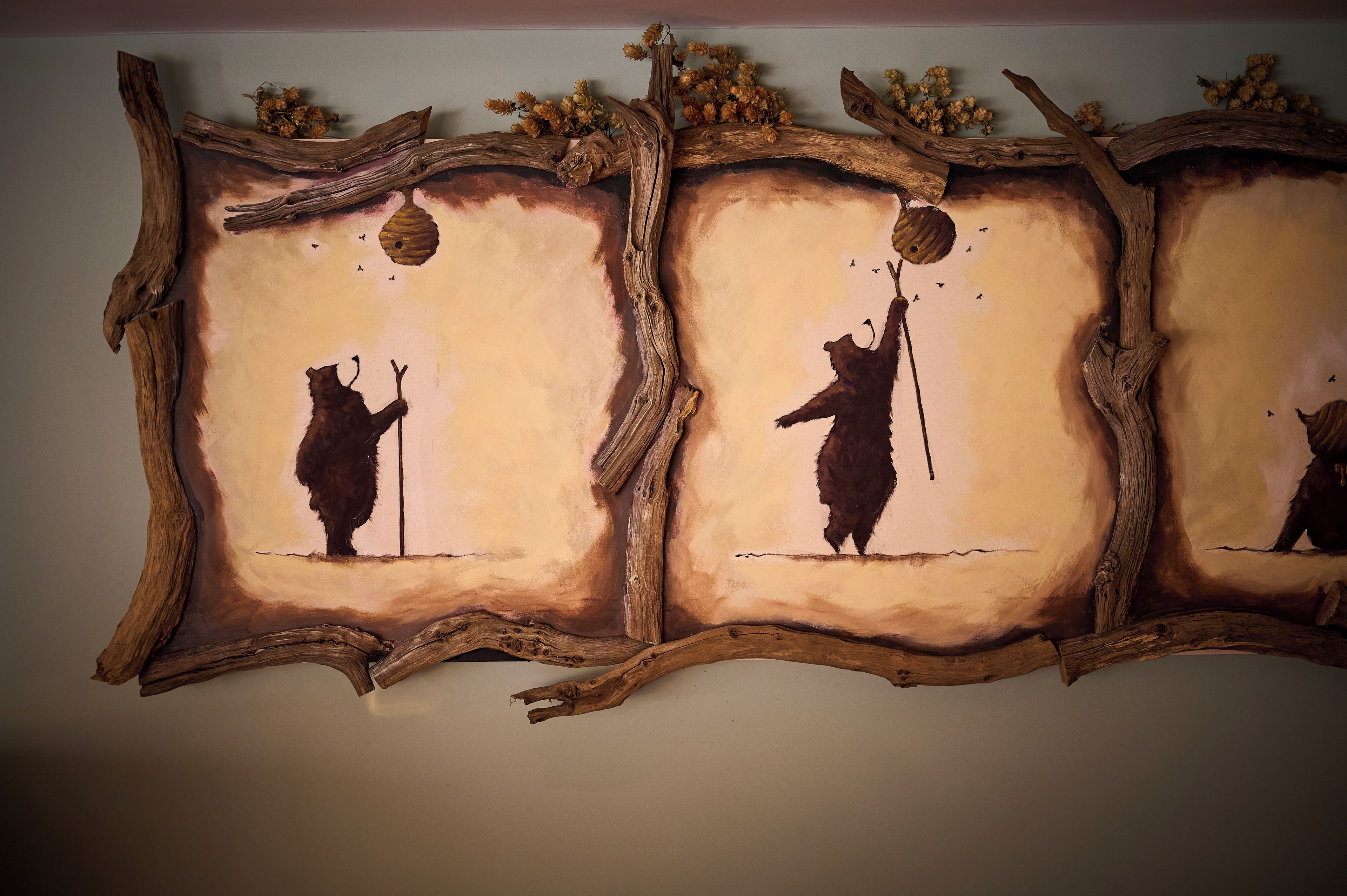 Une œuvre d’art murale représentant la silhouette d’un ours tenant un bâton, le tout sur un fond texturé.