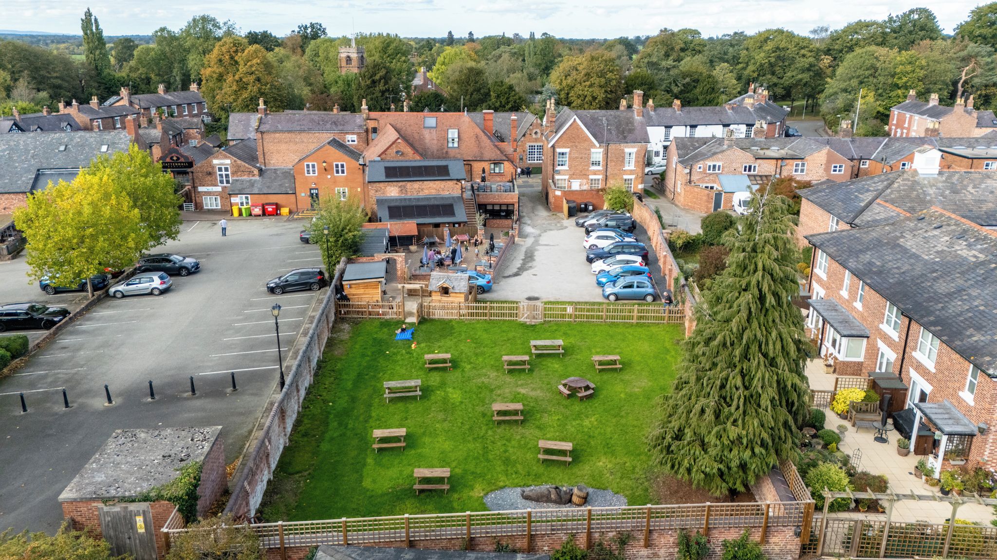 A courtyard with multiple seating areas, a parking lot, and a row of residential buildings.