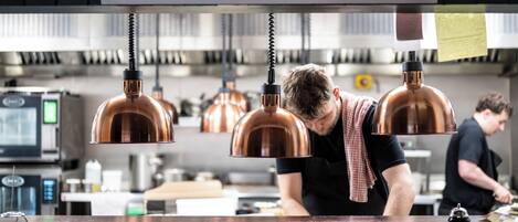 A kitchen with copper pendant lights, a wooden countertop, and a person working at the counter.