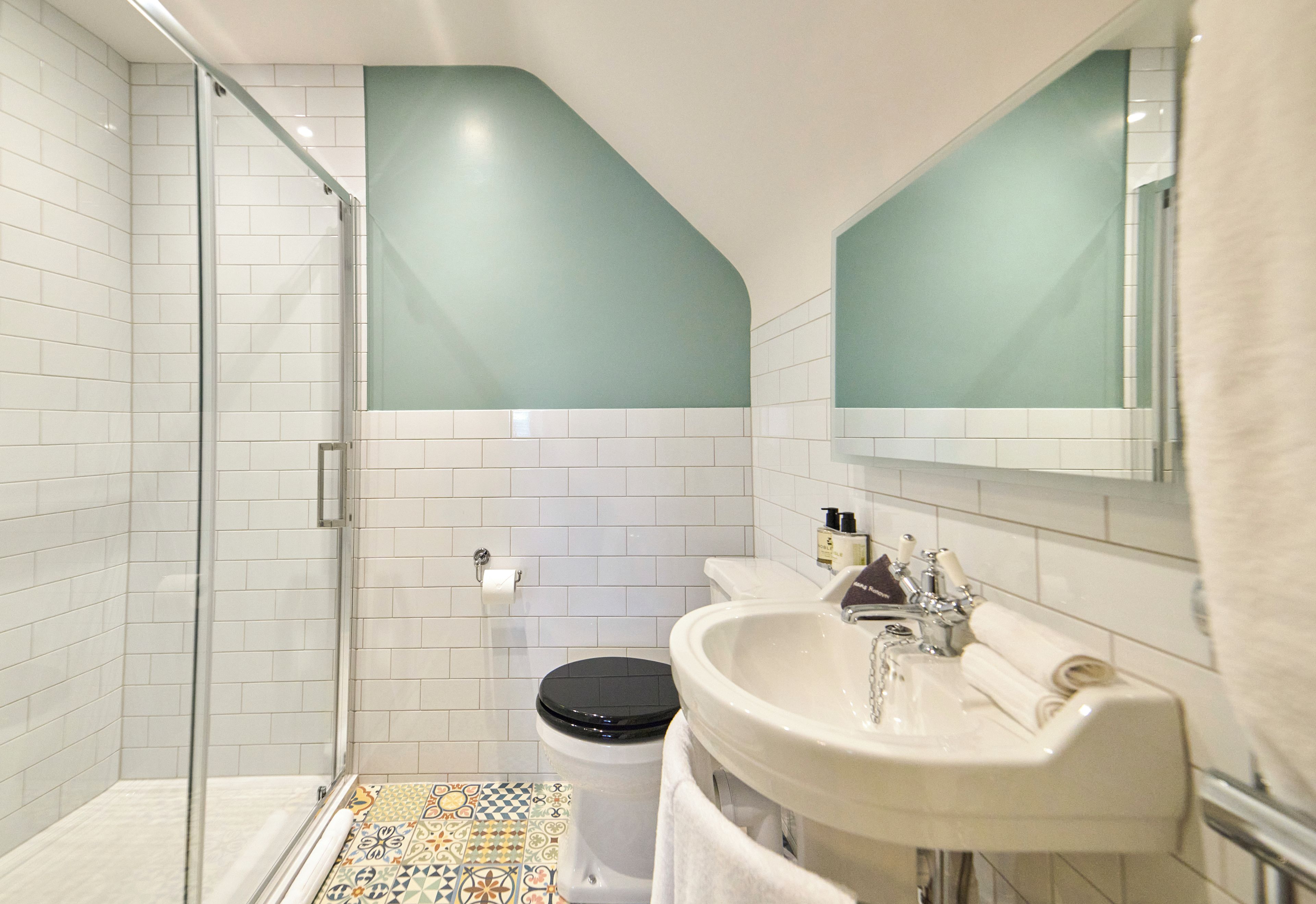 A bathroom with a shower, toilet, sink, and a mirror.