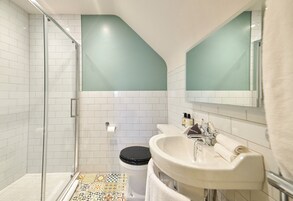 Un baño con ducha, inodoro, lavabo y espejo.