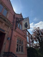 A brick building with a sign reading 'The Bear' and a coat of arms.